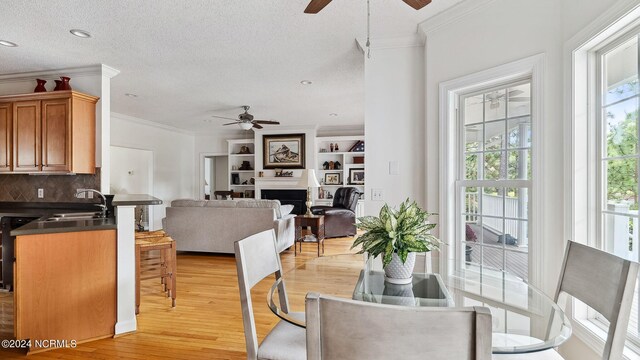 dining area featuring a notable chandelier, ornamental molding, light hardwood / wood-style flooring, and a textured ceiling