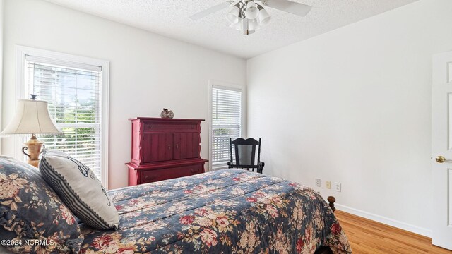 bedroom with a textured ceiling, hardwood / wood-style floors, and multiple windows