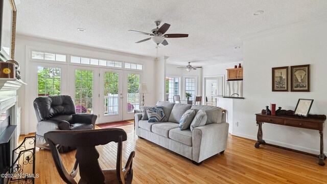 living area with ornamental molding, a textured ceiling, and light hardwood / wood-style floors