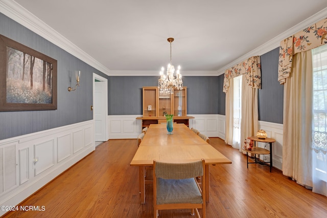 dining area with crown molding, an inviting chandelier, and light wood-type flooring