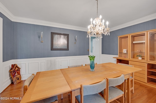 dining space featuring a notable chandelier, crown molding, and light hardwood / wood-style flooring