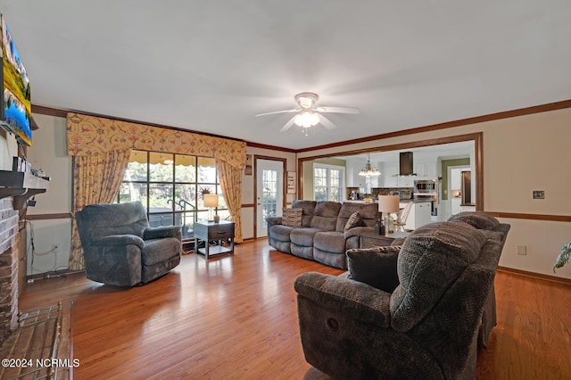 living room featuring wood-type flooring, ornamental molding, and ceiling fan