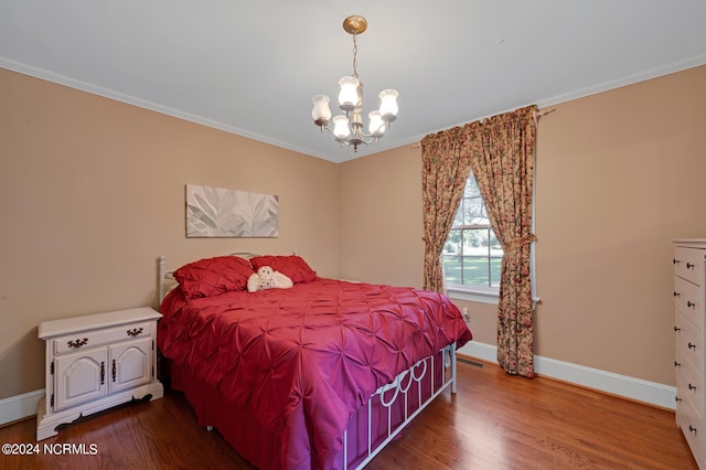 bedroom with crown molding, hardwood / wood-style floors, and a chandelier