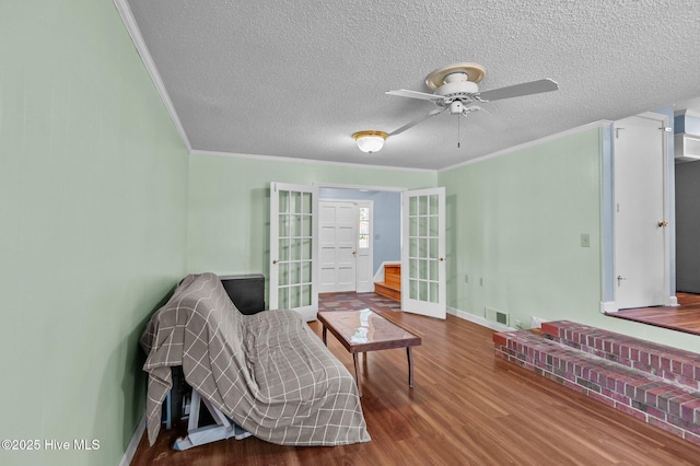 living area with ceiling fan, french doors, hardwood / wood-style floors, and ornamental molding