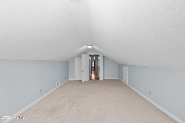 bonus room with a textured ceiling, light colored carpet, and lofted ceiling