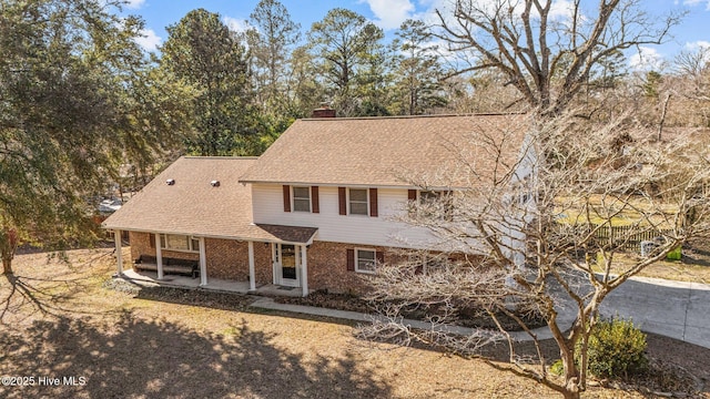 217 Randomwood Ln, River Bend, NC 28562 - view of front of property featuring brick siding, a chimney, covered porch, and roof with shingles