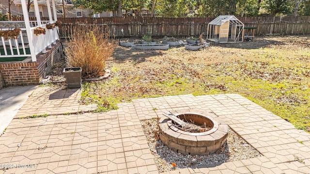 view of patio with a shed and an outdoor fire pit