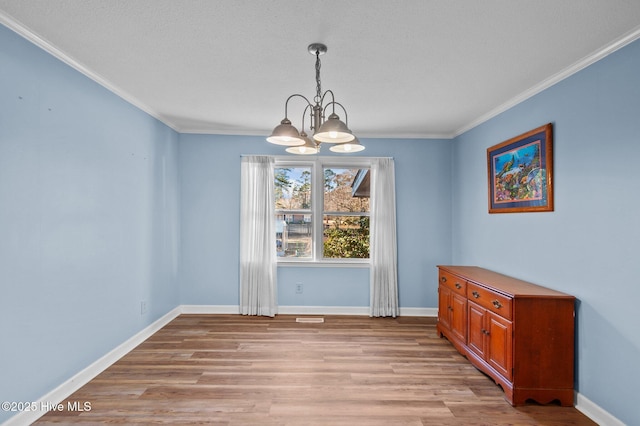 dining area featuring light hardwood / wood-style floors, crown molding, and a chandelier