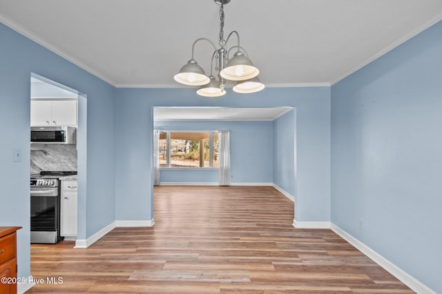 unfurnished dining area with light hardwood / wood-style floors, ornamental molding, and a notable chandelier