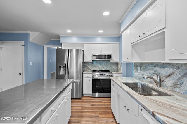 kitchen featuring hardwood / wood-style floors, white cabinets, sink, appliances with stainless steel finishes, and tasteful backsplash