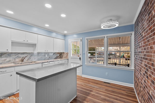 kitchen with decorative backsplash, a kitchen island, white cabinetry, and brick wall