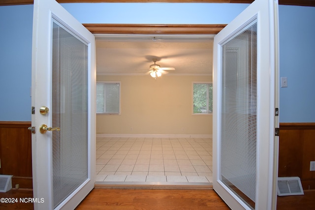 hall with wooden walls, crown molding, and light tile patterned floors