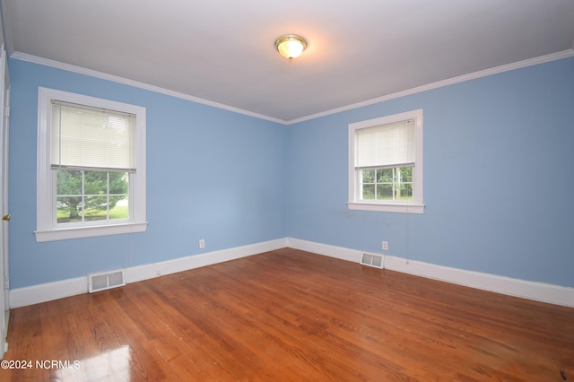 spare room featuring wood-type flooring and crown molding