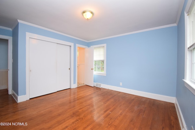 unfurnished bedroom featuring crown molding, a closet, and hardwood / wood-style flooring