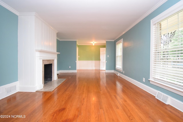 unfurnished living room with wood-type flooring, a high end fireplace, and crown molding