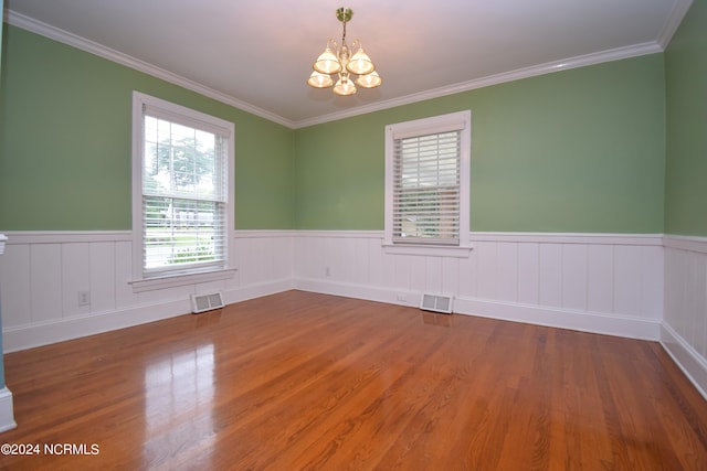 spare room with crown molding, an inviting chandelier, and hardwood / wood-style flooring