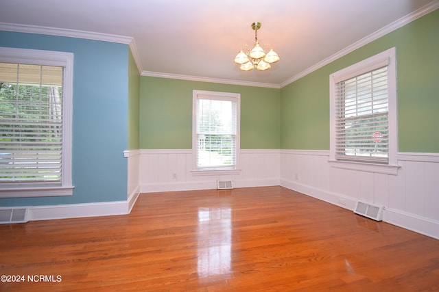 unfurnished room with crown molding, hardwood / wood-style floors, a chandelier, and a healthy amount of sunlight