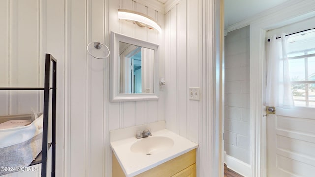 bathroom with wood walls, vanity, and crown molding