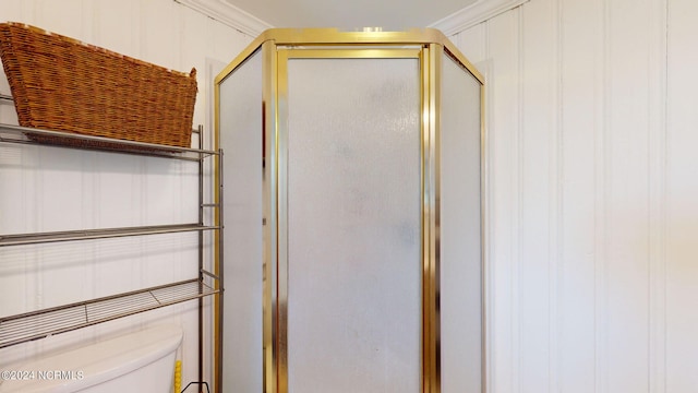 bathroom featuring crown molding, toilet, and a shower with door