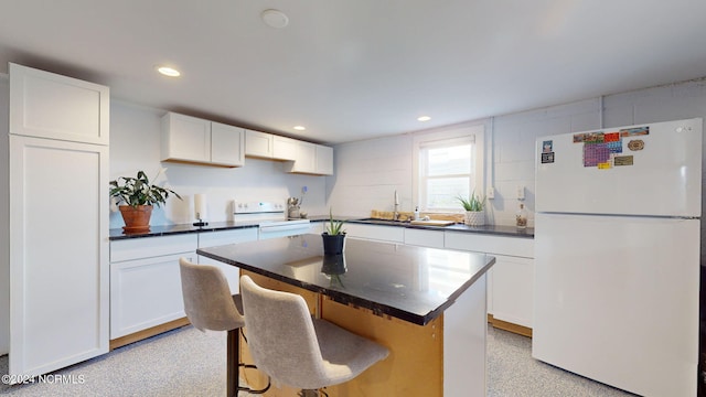 kitchen with a kitchen breakfast bar, white appliances, white cabinetry, and a center island