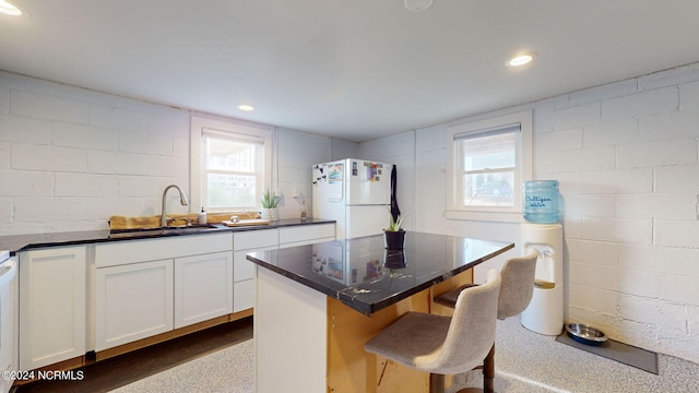 kitchen with white cabinets, white refrigerator, sink, a kitchen island, and a kitchen breakfast bar