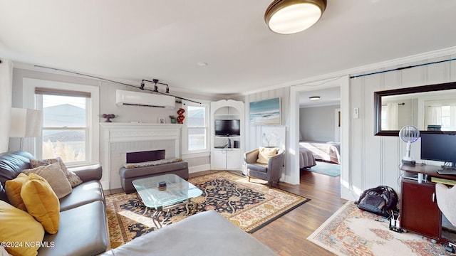 living room featuring ornamental molding, a brick fireplace, hardwood / wood-style flooring, and a wall mounted AC