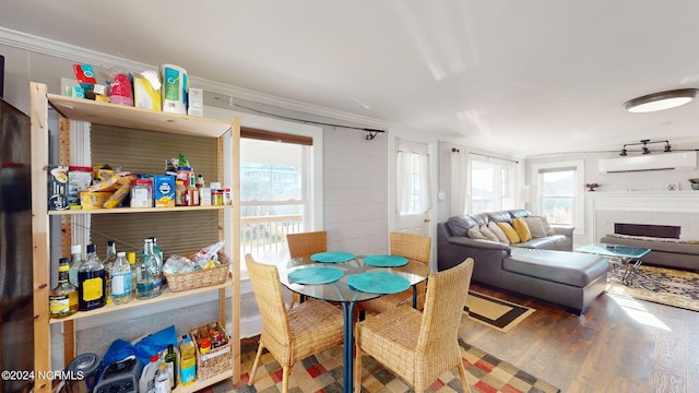 dining area featuring wood-type flooring, crown molding, and a wall mounted air conditioner