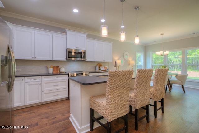 572 Hearthside Dr SE, Bolivia, NC 28422 - kitchen with stainless steel appliances, dark wood-type flooring, crown molding, tasteful backsplash, and dark countertops