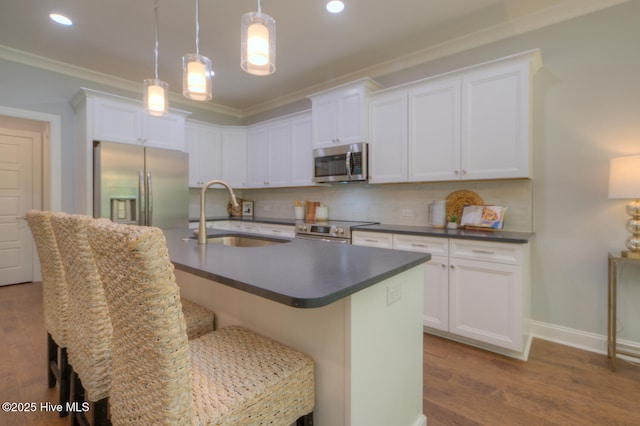 572 Hearthside Dr SE, Bolivia, NC 28422 - kitchen featuring appliances with stainless steel finishes, a sink, dark countertops, an island with sink, and ornamental molding