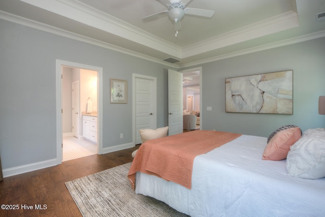 572 Hearthside Dr SE, Bolivia, NC 28422 - bedroom with a tray ceiling, wood finished floors, crown molding, connected bathroom, and baseboards