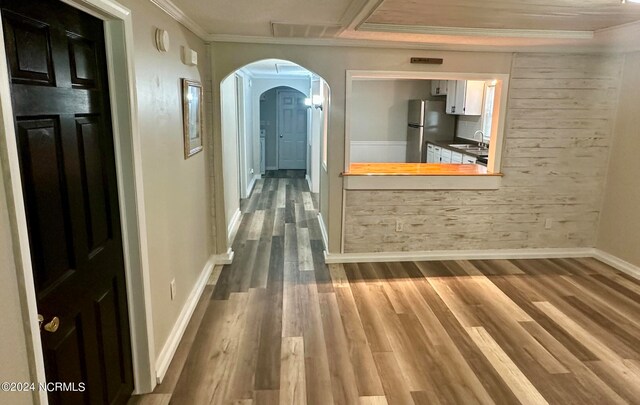 hall with ornamental molding, wood-type flooring, and sink