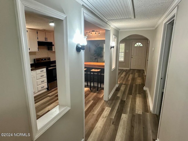 interior space featuring a textured ceiling, crown molding, and dark wood-type flooring