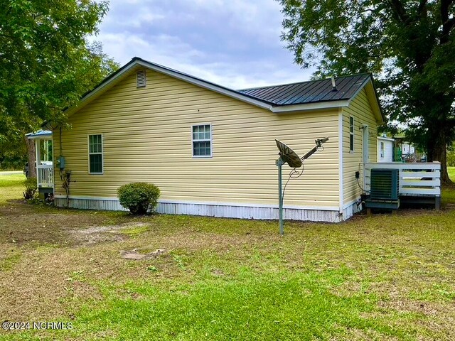 view of side of home featuring a wooden deck, central AC, and a yard