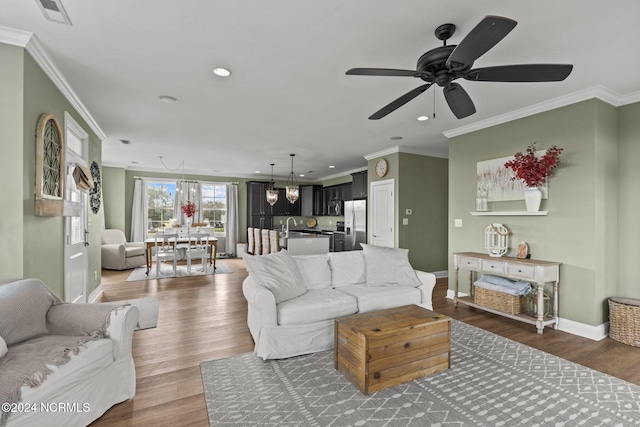 living room with ceiling fan, ornamental molding, sink, and dark hardwood / wood-style flooring