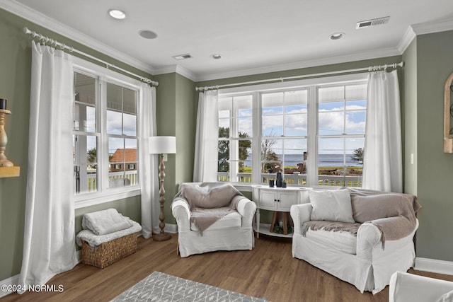 living area featuring baseboards, ornamental molding, wood finished floors, and visible vents