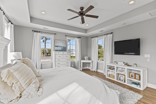 bedroom featuring ceiling fan, a raised ceiling, and wood-type flooring