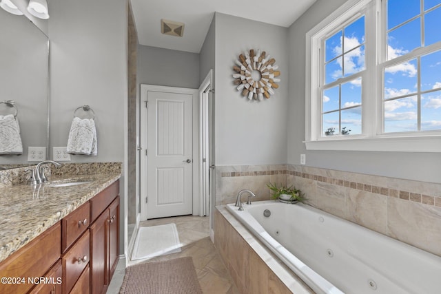 bathroom featuring tiled tub, tile patterned flooring, and vanity