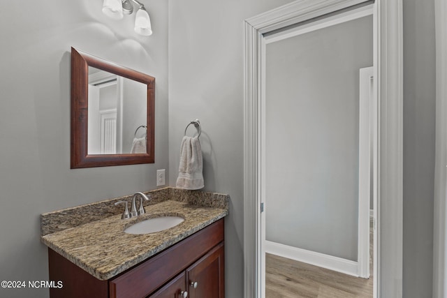 bathroom featuring baseboards, wood finished floors, and vanity