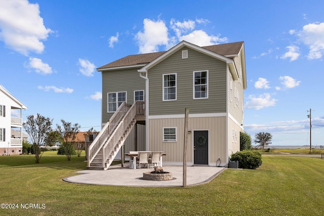 back of property with a lawn, a patio, and an outdoor fire pit