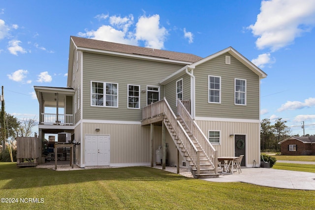 rear view of property with a yard, stairs, and a patio