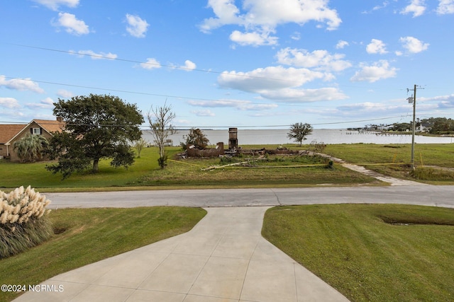 view of property's community with a water view, a yard, and curved driveway