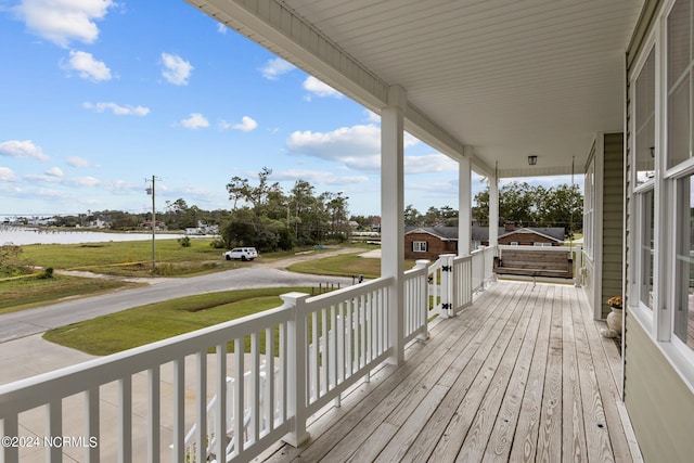 deck with covered porch and a water view
