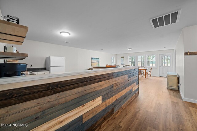 bar with sink, white refrigerator, and light wood-type flooring