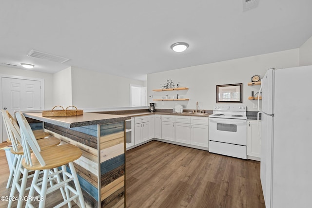 kitchen featuring sink, a kitchen breakfast bar, hardwood / wood-style flooring, white appliances, and white cabinets