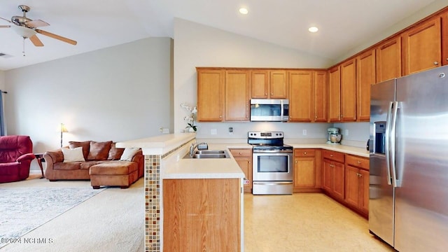 kitchen featuring a peninsula, a sink, open floor plan, vaulted ceiling, and appliances with stainless steel finishes