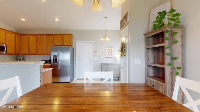 kitchen with stainless steel appliances, brown cabinets, light countertops, and hanging light fixtures