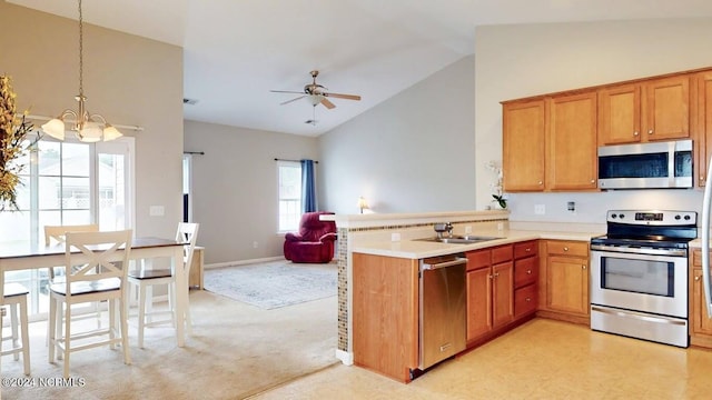 kitchen with open floor plan, a peninsula, stainless steel appliances, light countertops, and ceiling fan with notable chandelier