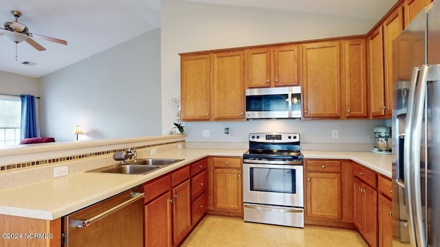 kitchen with stainless steel appliances, a peninsula, a sink, visible vents, and vaulted ceiling