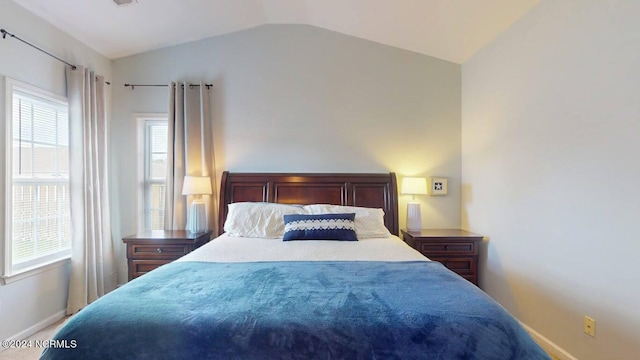 bedroom featuring lofted ceiling, multiple windows, and baseboards