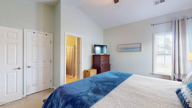 carpeted bedroom featuring connected bathroom, visible vents, vaulted ceiling, and ceiling fan